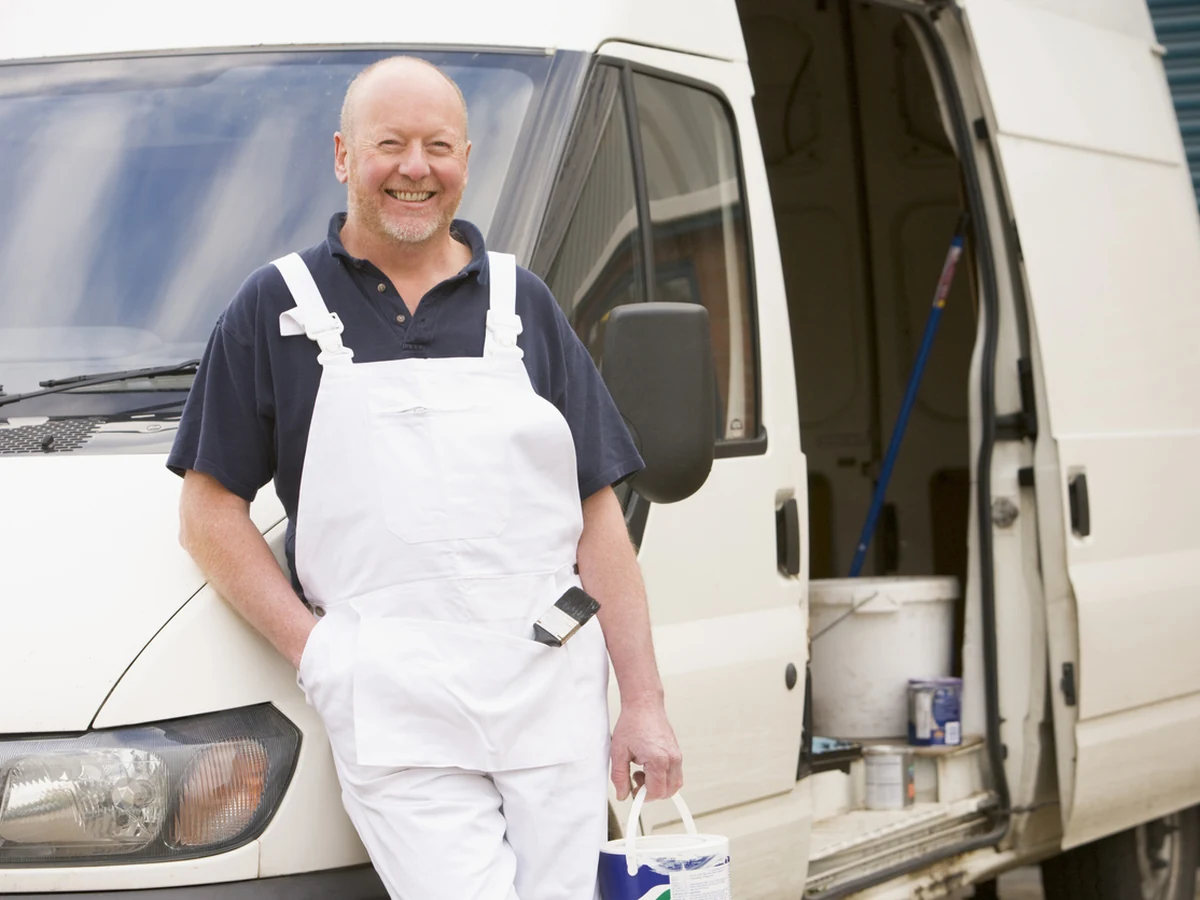 Smiling decorator in overalls ready for renovation work in Coventry
